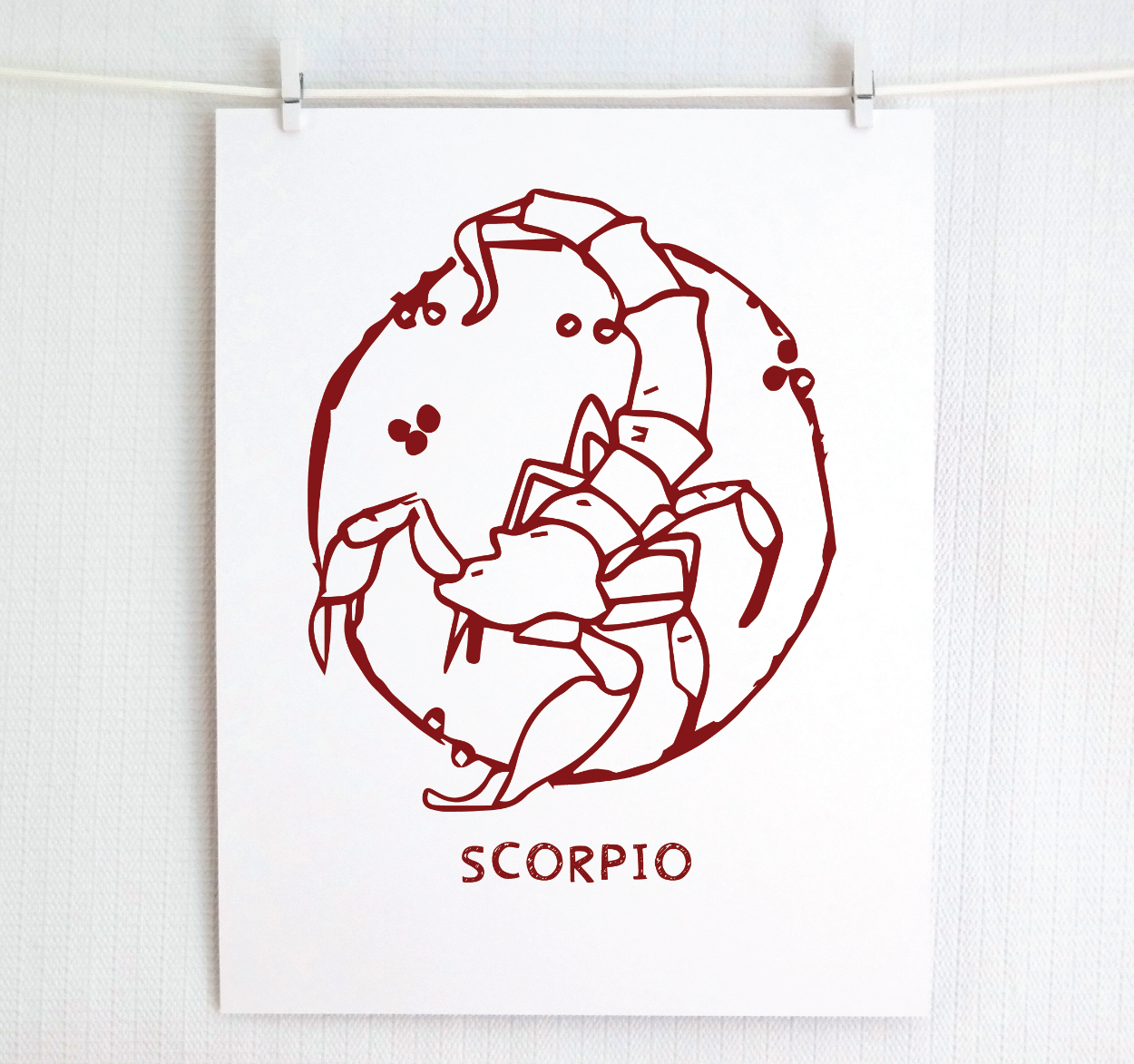 An illustration of the SCORPIO Zodiac sign as a scorpion, printed on paper with the word ‘SCORPIO’ at the bottom in cranberry.
