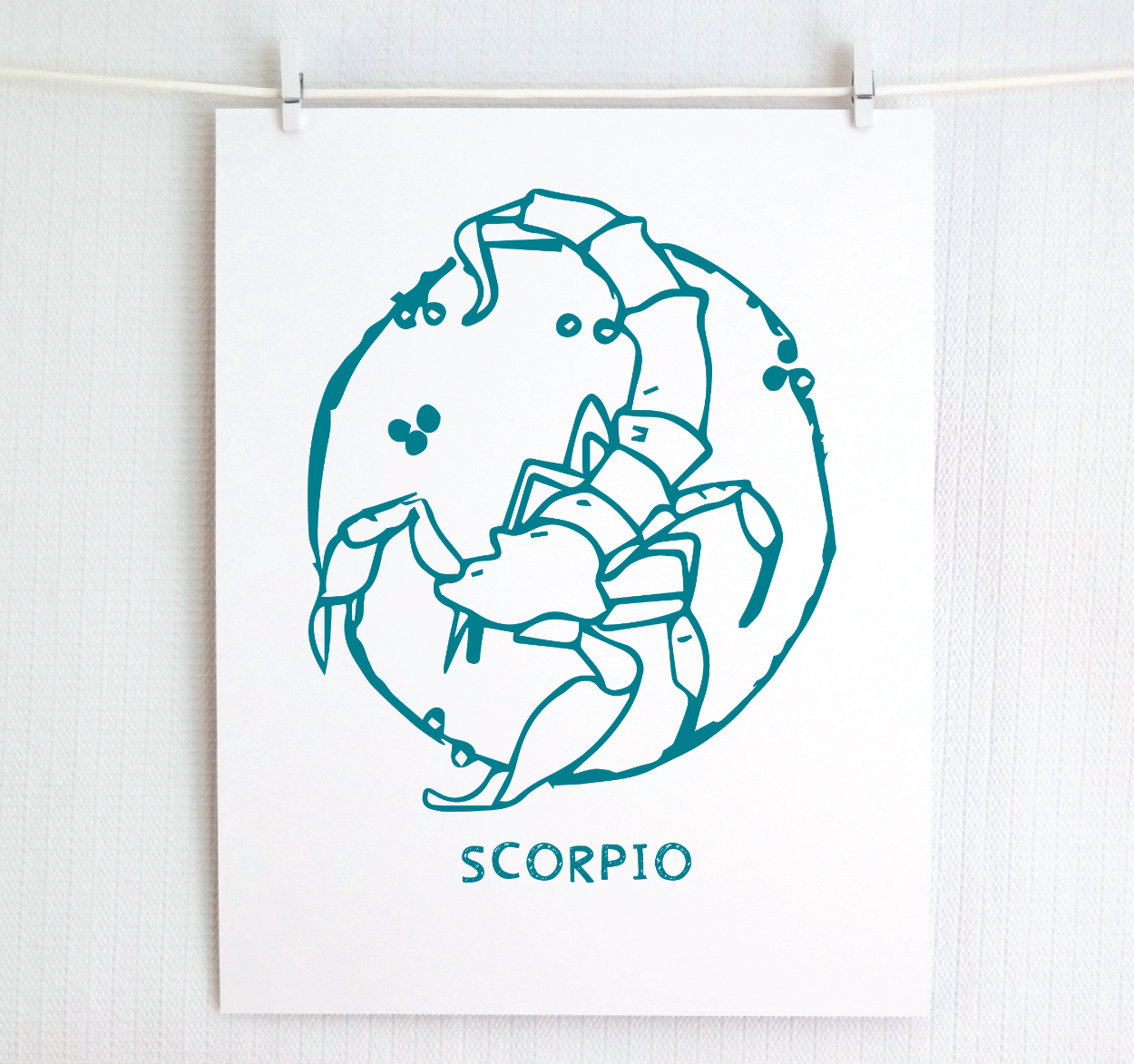 An illustration of the SCORPIO Zodiac sign as a scorpion, printed on paper with the word ‘SCORPIO’ at the bottom in dark teal.