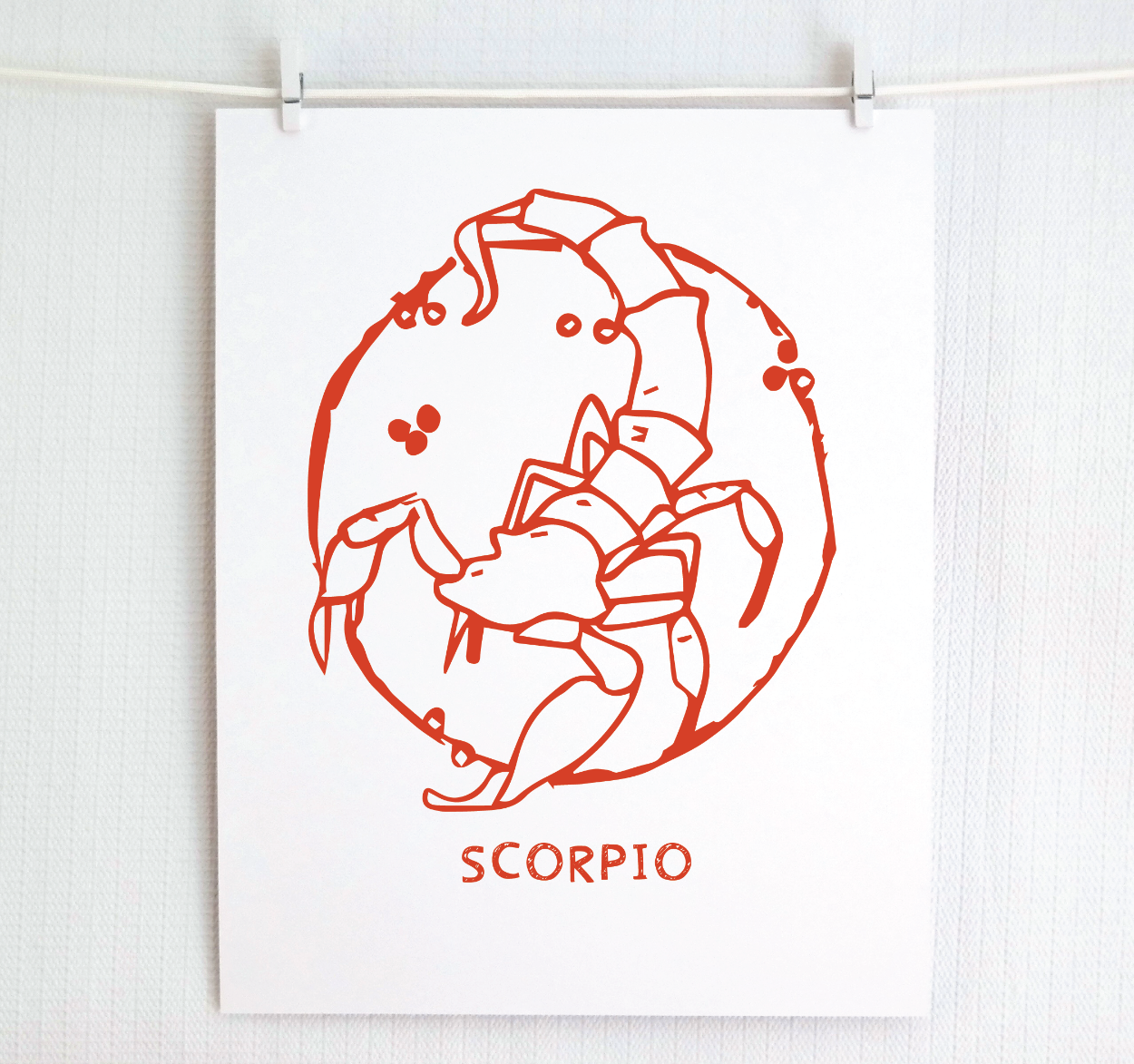 An illustration of the SCORPIO Zodiac sign as a scorpion, printed on paper with the word ‘SCORPIO’ at the bottom in red.