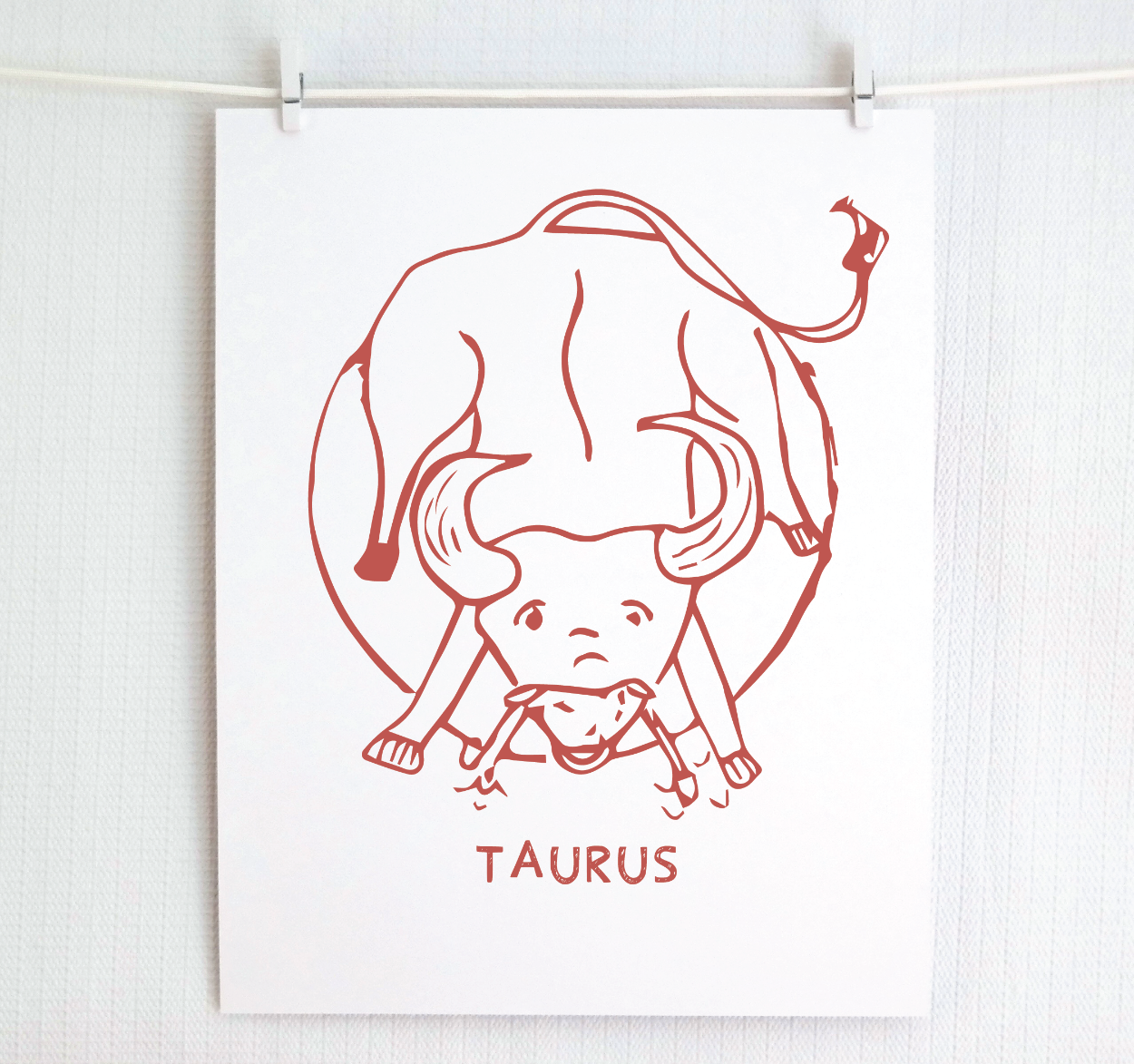 An illustration of the TAURUS Zodiac sign as a bull, printed on paper with the word ‘TAURUS’ at the bottom in blush.