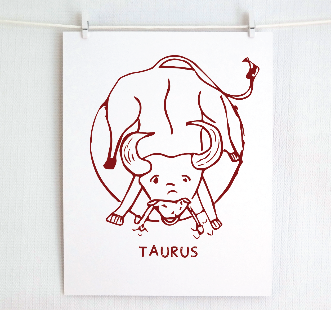 An illustration of the TAURUS Zodiac sign as a bull, printed on paper with the word ‘TAURUS’ at the bottom in cranberry.