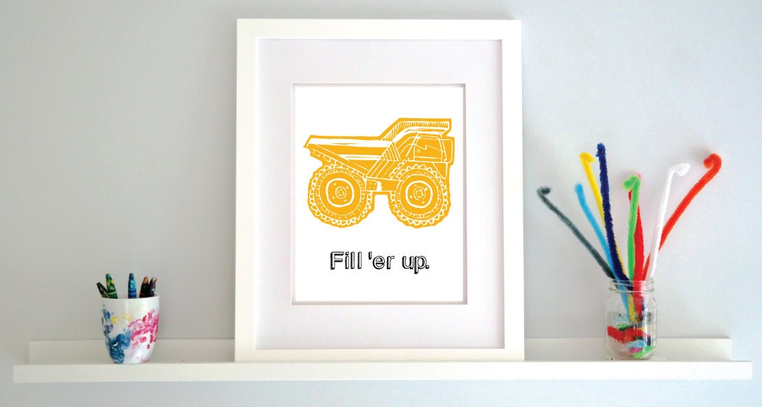 A framed artwork featuring a stylized construction vehicle in yellow on a white background, with the phrase 'Fill 'er up.'
